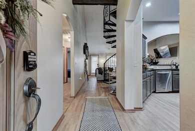 Entrance foyer with light wood-style floors, arched walkways, stairway