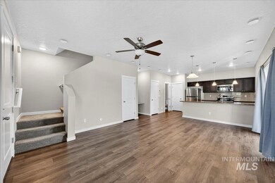 Unfurnished living room with ceiling fan, stairway, dark wood-style flooring, and a textured ceiling