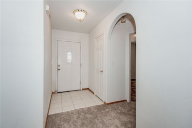 Entryway with light colored carpet, arched walkway