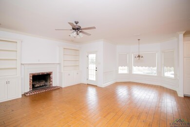Unfurnished living room with built in features, ornamental molding, a fireplace, light wood-type flooring, and ceiling fan with notable chandelier