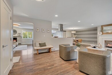 Living room with a lit fireplace, light wood finished floors, and recessed lighting
