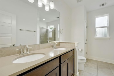 Bathroom with toilet, a shower stall, double vani