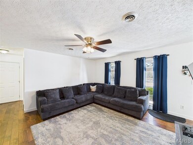 Living area with hardwood / wood-style floors, a textured ceiling, and ceiling fan