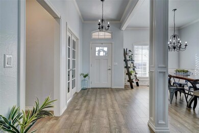 Entryway with an inviting chandelier, crown moldin