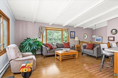 Living room featuring beamed ceiling, light hardwo
