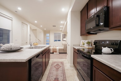 Kitchen with black appliances, recessed lighting, dark brown cabinetry, open floor plan, and light countertops