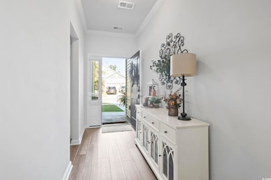Doorway with ornamental molding and wood finished floors