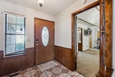 Foyer entrance featuring wainscoting, a textured ceiling, wooden walls, light colored carpet, and light tile patterned floors