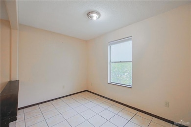 Empty room featuring baseboards, a textured ceiling, and light tile patterned flooring