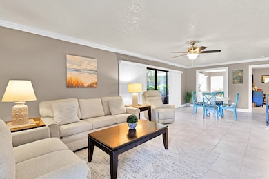Living area with crown molding, a textured ceiling, ceiling fan, and light tile patterned floors