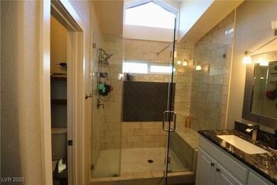 Full bathroom with a stall shower, vanity, and a textured wall