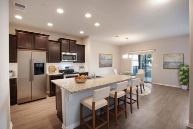 Kitchen featuring dark brown cabinets, appliances with stainless steel finishes, backsplash, a chandelier, and light wood finished floors