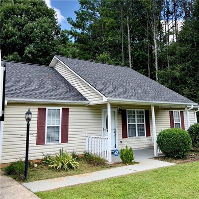 Single story home with a shingled roof, a porch, and a front lawn