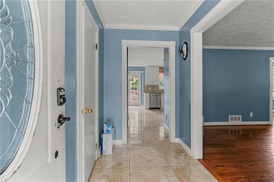 Hallway with a textured ceiling, crown molding, and wood finished floors