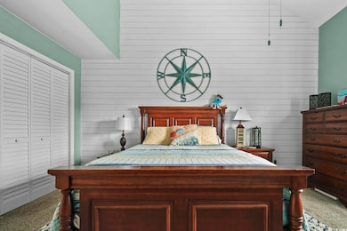 Bedroom featuring carpet, a closet, lofted ceiling, and wooden walls