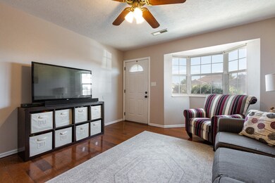 Living room featuring dark wood-style floors, a ceiling fan, and a textured ceiling