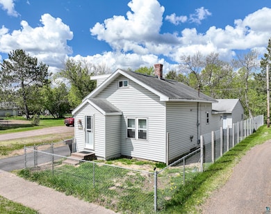 View of side of property featuring a fenced front yard and a gate