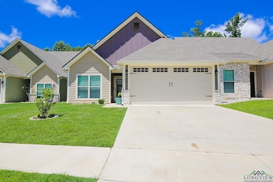 View of front of home with board and batten siding, a garage, stone siding, driveway, and a front lawn