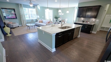 Kitchen with a sink, dark wood-style flooring, open floor plan, a center island with sink, and tasteful backsplash