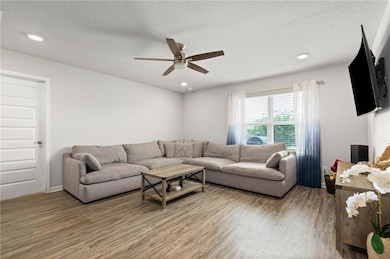 Living area featuring wood finished floors, ceiling fan, recessed lighting, and a textured ceiling