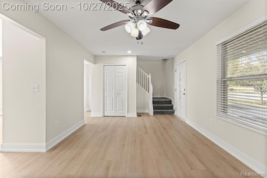 Unfurnished living room with stairway, light wood-style flooring, and ceiling fan