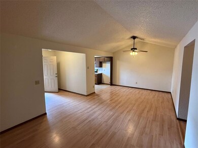 Empty room with a textured ceiling, light wood fin
