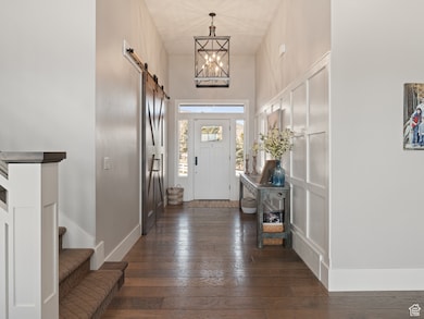 Entrance foyer with a barn door, baseboards, dark wood-style flooring, a towering ceiling, and stairs
