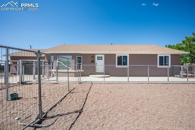 View of front of property with stucco siding and a patio from inside the fully fenced pet area.