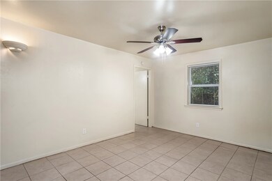 Empty room featuring a ceiling fan, light tile pat