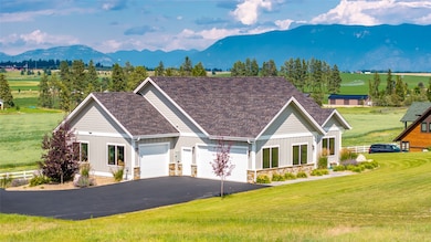 View of front of property with an attached garage, a mountain view, asphalt driveway, and a front lawn