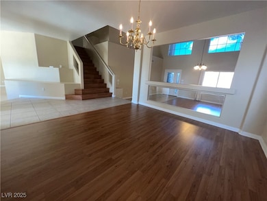 Unfurnished living room featuring a chandelier, dark wood-style floors, and stairs
