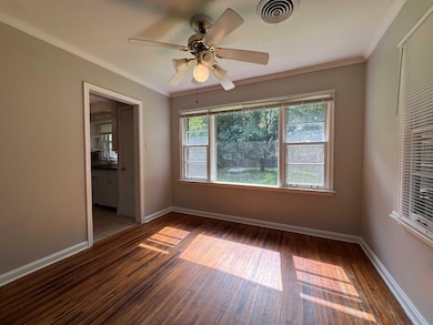Spacious dining area with picture windows overlooking beautiful large rear yard. This area features wood finished floors, baseboards, a ceiling fan, and ornamental molding