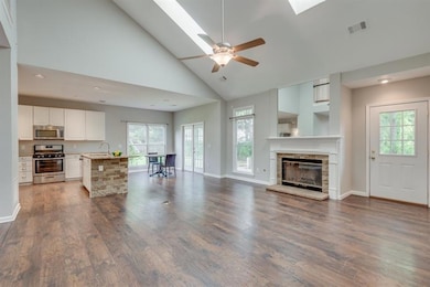 Open concept with view from kitchen to family room with vaulted ceiling and fireplace.