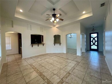 Spare room with ceiling fan, a tray ceiling, baseboards, recessed lighting, and arched walkways