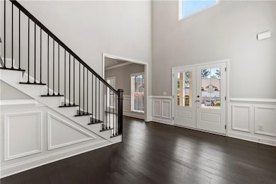 Entryway featuring a decorative wall, plenty of natural light, a high ceiling, dark wood finished floors, and stairs