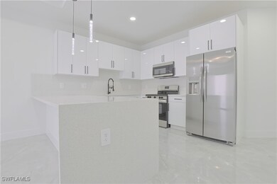 Kitchen featuring a peninsula, white cabinets, app