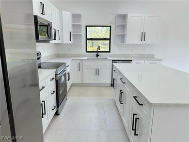 Kitchen with white cabinetry, open shelves, a sink