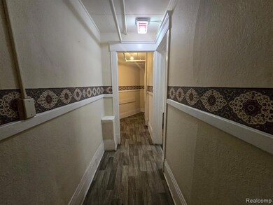 Hall with a textured wall, dark wood-style floors, and crown molding