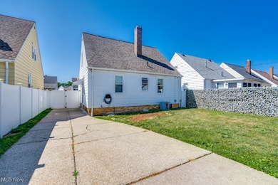 Back of property with central air condition unit and a lawn