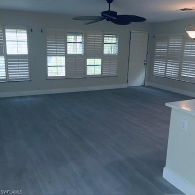 Unfurnished living room featuring dark wood-style floors and a ceiling fan