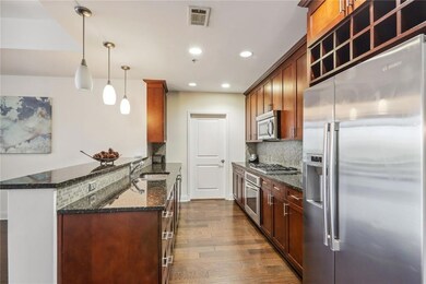 Kitchen featuring decorative light fixtures, dark stone countertops, dark wood-type flooring, sink, and tasteful backsplash