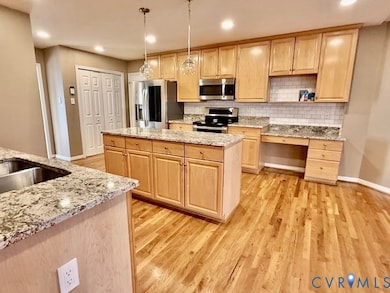 Kitchen with light brown cabinets, decorative backsplash, recessed lighting, light stone counters, and open shelves