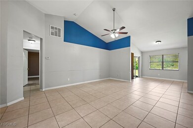 Empty room with high vaulted ceiling, light tile patterned flooring, and ceiling fan