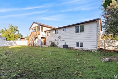 Rear view of property featuring a fenced backyard, stairway, and a balcony