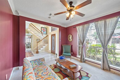 The formal living room features high ceilings and crown moulding with ceiling fan and a lot of natural light.