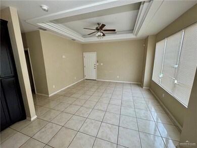 Unfurnished room with light tile patterned floors, a tray ceiling, and baseboards