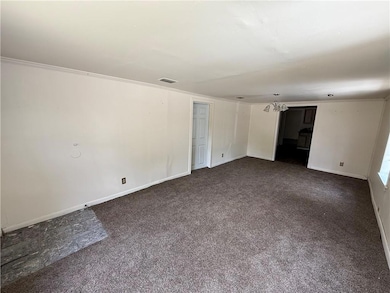 Empty room featuring dark colored carpet and a chandelier