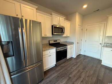 Kitchen with white cabinetry, light stone counters