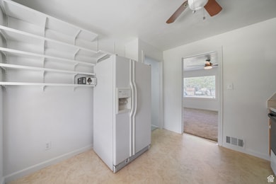 Kitchen with white fridge with ice dispenser, ceiling fan, open shelves, and light floors