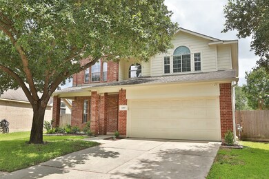 Two-story suburban house with red brick, two car garage with storage racks, sprinklers and full gutters.